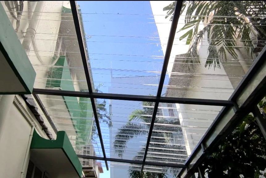 Clear translucent roof panels supported by a dark metal canopy frame between buildings